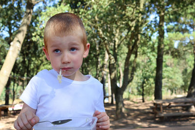 A blond boy with noodles in his mouth rolls his eyes and looks into the distance. disgruntled  boy.