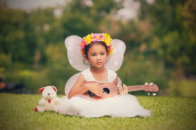 Cute baby girl sitting on grass in field