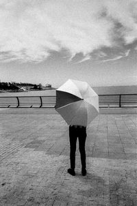 Rear view of man standing by sea against sky