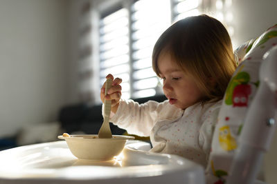 Two years old eats porridge by herself with a spoon. child development concept