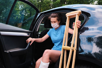 A woman with an injured leg gets into a car. orthopedic plaster, orthopedic crutches. 