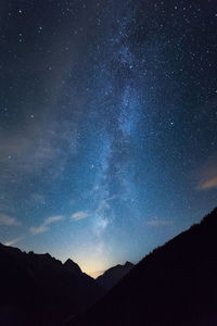 Low angle view of silhouette mountains against star field