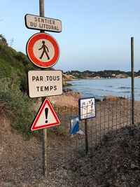 Information sign at beach against clear blue sky