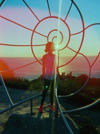 Rear view of woman standing by railing against sky