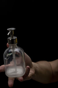 Midsection of man holding bottle against black background