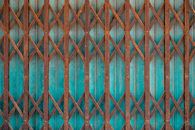 Full frame shot of metal fence against blue wall