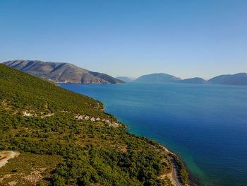 Scenic view of sea and mountains against clear blue sky