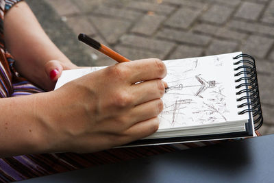 Cropped hands of woman drawing on book