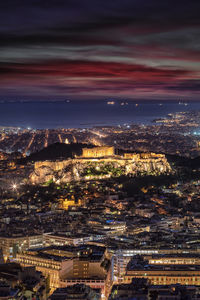 Aerial view of illuminated cityscape against cloudy sky at night