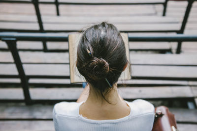 High angle view of woman reading book while sitting outdoors