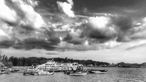 Boats in sea against cloudy sky
