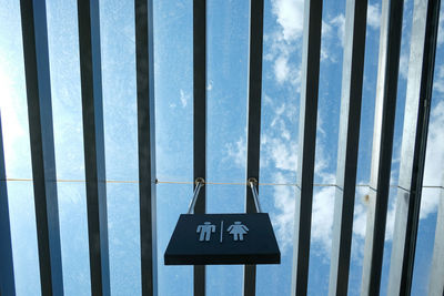 Low angle view of restroom sign hanging from pattern roof