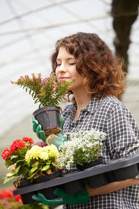 Woman holding flower pot standing outdoors