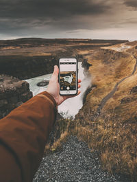 Person holding camera against sky