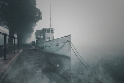 Boat moored on sea during winter against sky