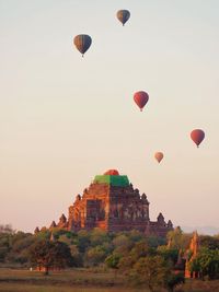 Hot air balloons flying over buildings against sky