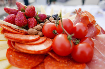 Close-up of strawberries in plate on table. salami, tomatoes.