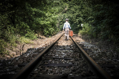 Rear view of person walking on railroad track