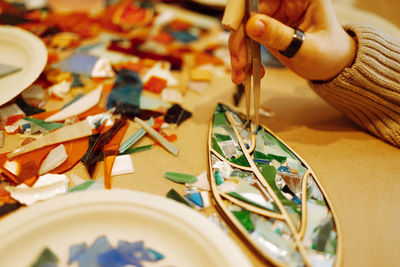 Cropped hand of woman painting on table