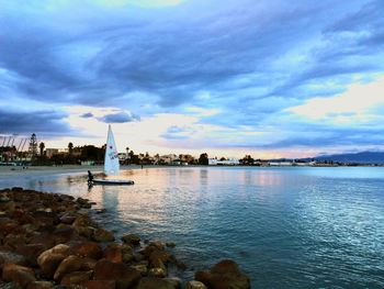 Boats in sea against cloudy sky