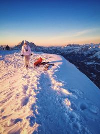 Female hiker walking on snowcapped mountain against sky