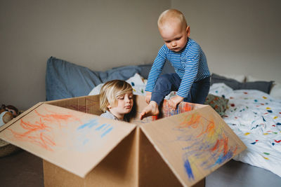 Young male kids playing and drawing in a box during lockdown