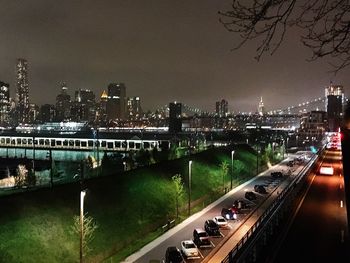 Illuminated bridge over river in city against sky at night
