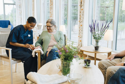 Senior woman getting her nails in shape from young female caretaker at nursing home