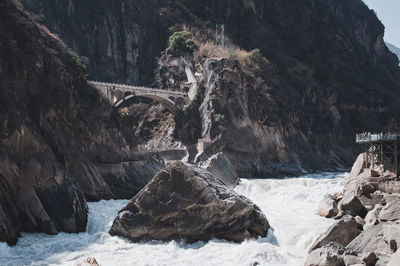 Low angle view of bridge by rock formation over river