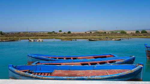 Boats moored on sea against clear blue sky