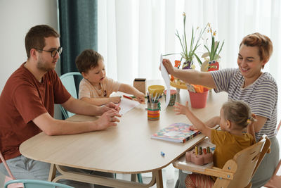 Family with kids having fun at home by the table, creating hand made art. mother father and children