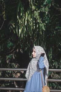 Woman standing by tree in forest