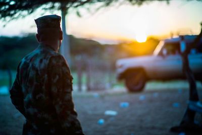 Rear view of man standing on road at sunset