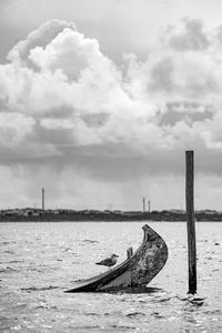 Old ship post in sea against sky