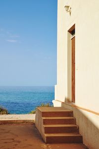 Staircase leading towards sea against sky