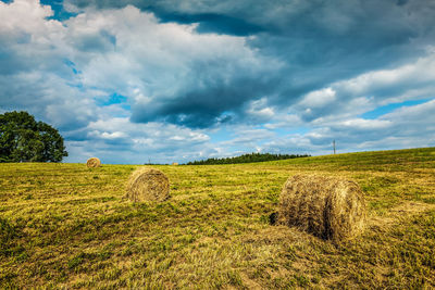 Hay bales on field against sky