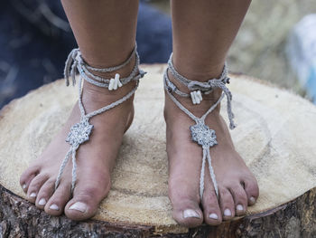 Low section of woman wearing anklet on tree stump