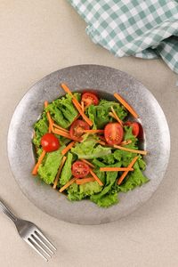 Simpel vegetable salad with tomato, carrot, and lettuce. top view