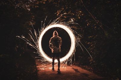 Man standing on illuminated ferris wheel at night