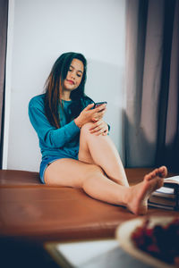 Young woman using mobile phone at home