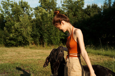 Woman standing on field against trees