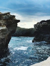 Rock formations by sea against sky