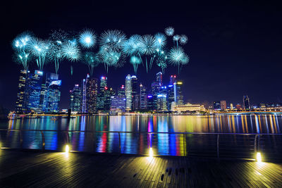 Firework display over river and illuminated buildings at night