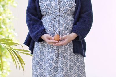 Midsection of woman holding umbrella standing outdoors