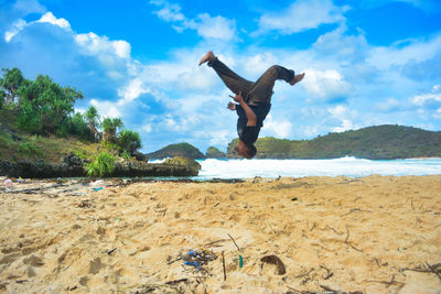 Full length of man in mid-air at beach 