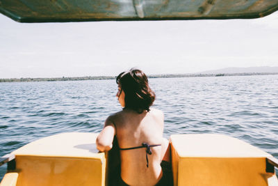 Rear view of young woman traveling on boat at sea