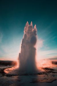 Scenic view of geyser erupting against sky