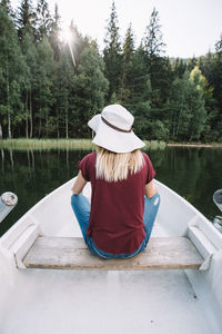 Rear view of woman sitting on boat in lake