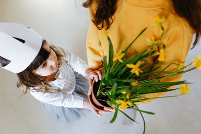 High angle view on two children holding pot with daffodil plant