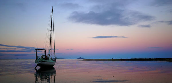 Sailboat sailing on sea against sky during sunset